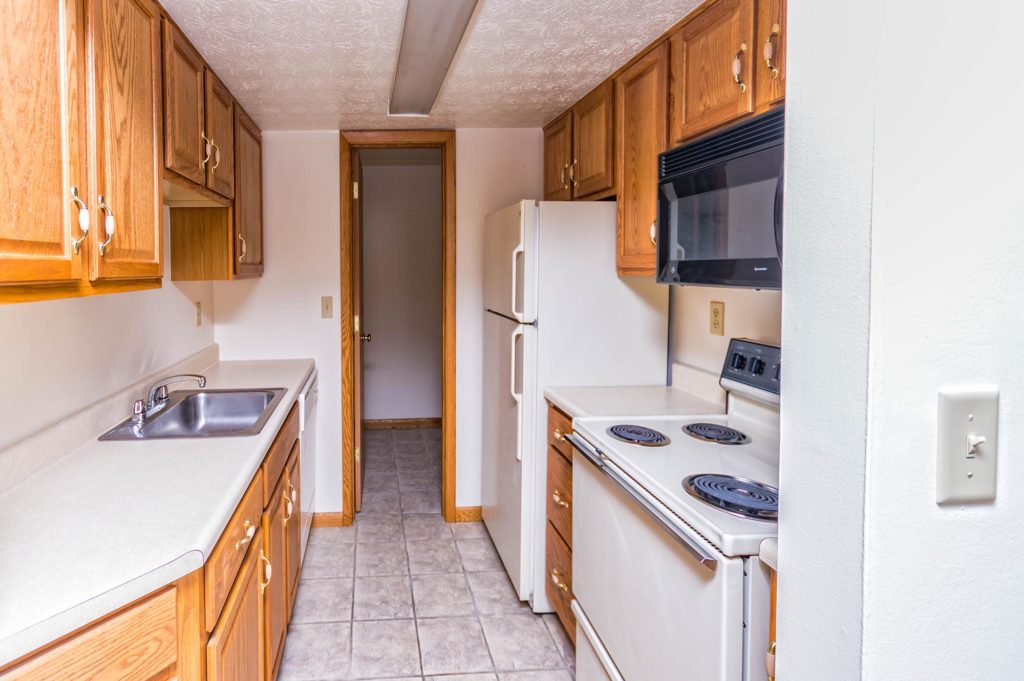 Fully equipped kitchen with stove, refrigerator, microwave, and dishwasher with tile flooring.