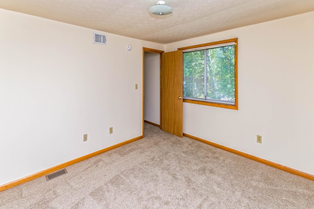 Plus tan carpeting in bedroom, with two windows for natural lighting.