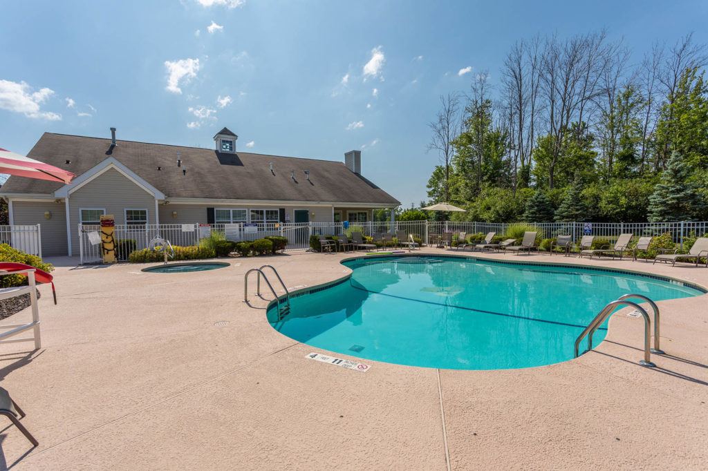 Relaxing oasis with an inground swimming pool, inviting hot tub, and spacious sundeck surrounded by additional sun chairs, perfect for unwinding and soaking up the sun.