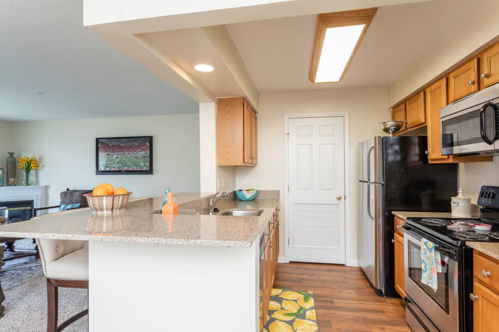 Modern kitchen showcasing elegant quartz countertops, stylish maple cabinetry, and durable LVP flooring, complete with a welcoming breakfast bar for casual dining.