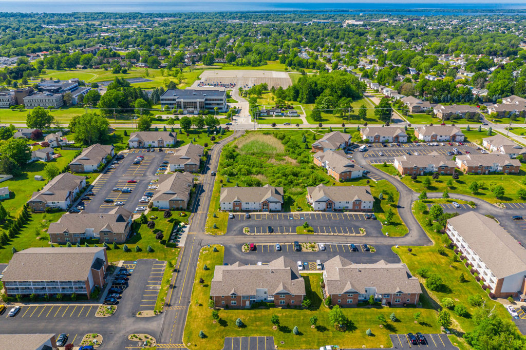 A breathtaking aerial view of the Laurel Springs Apartment Community, showcasing its convenient location near LECOM School and the stunning Lake Erie. The apartments offer easy access to both the school and the picturesque lake.