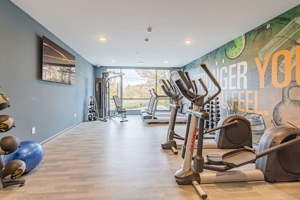 Resident fitness room with elliptical, treadmill, free weights, and weight machine