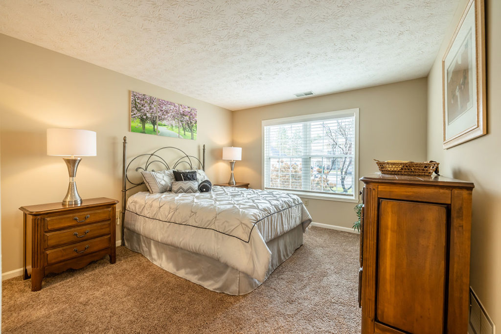 Large master bedroom with tan carpeting and window for extra light.