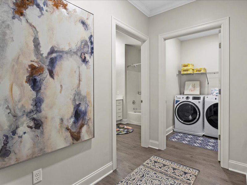 A laundry room with a washer and dryer and storage shelf.