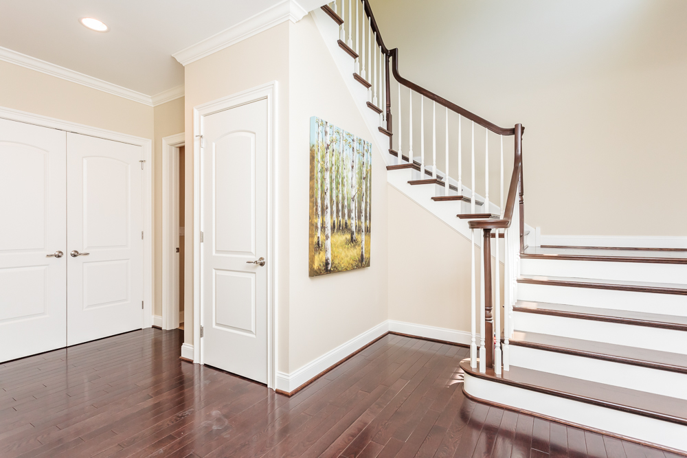 Entrance and view of the staircase leading to the upstairs. Dark hardwood flooring throughout entrance as well as on stiarcase..