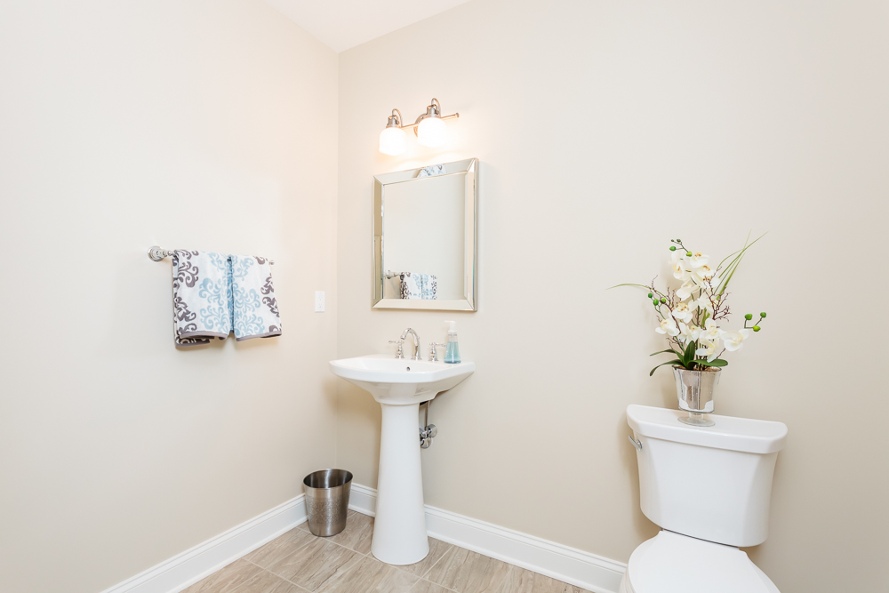 Powder room with pedestal sink and toilet with light tile flooring