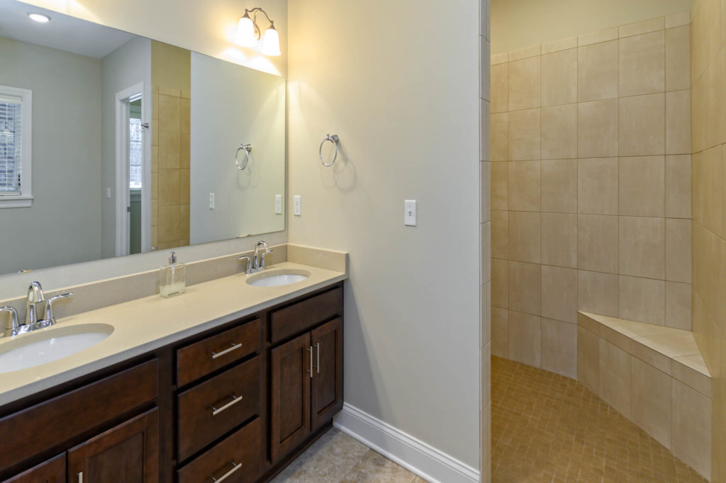 Double vanity bathroom with tiled walk-in shower at Carriage Home
