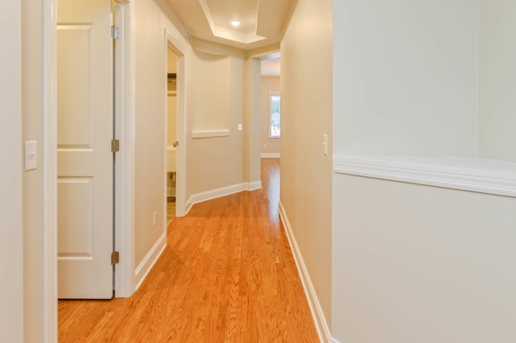 Carriage home hallway leading into living room. Hardwood flooring is found throughout home.