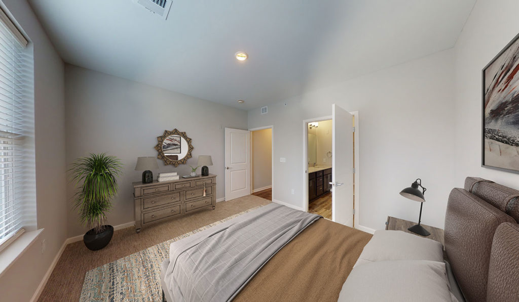 Carpeted bedroom view with access to private bathroom for the 2 bedroom floor plan