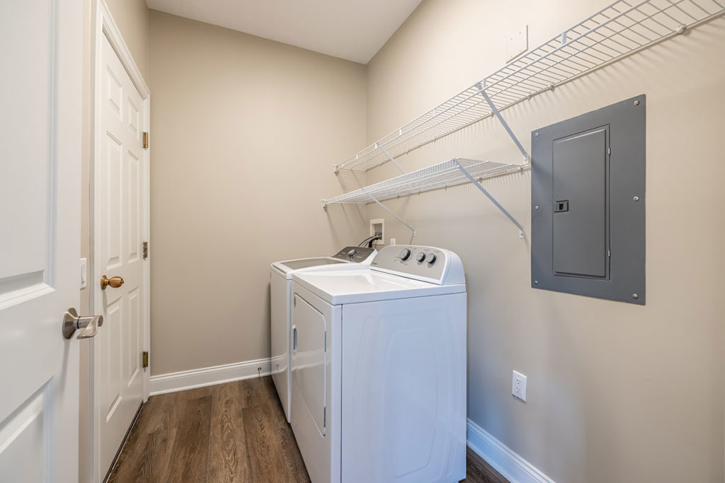 Townhome first-floor laundry with room for a full-size washer and dryer and extra shelving for additional storage
