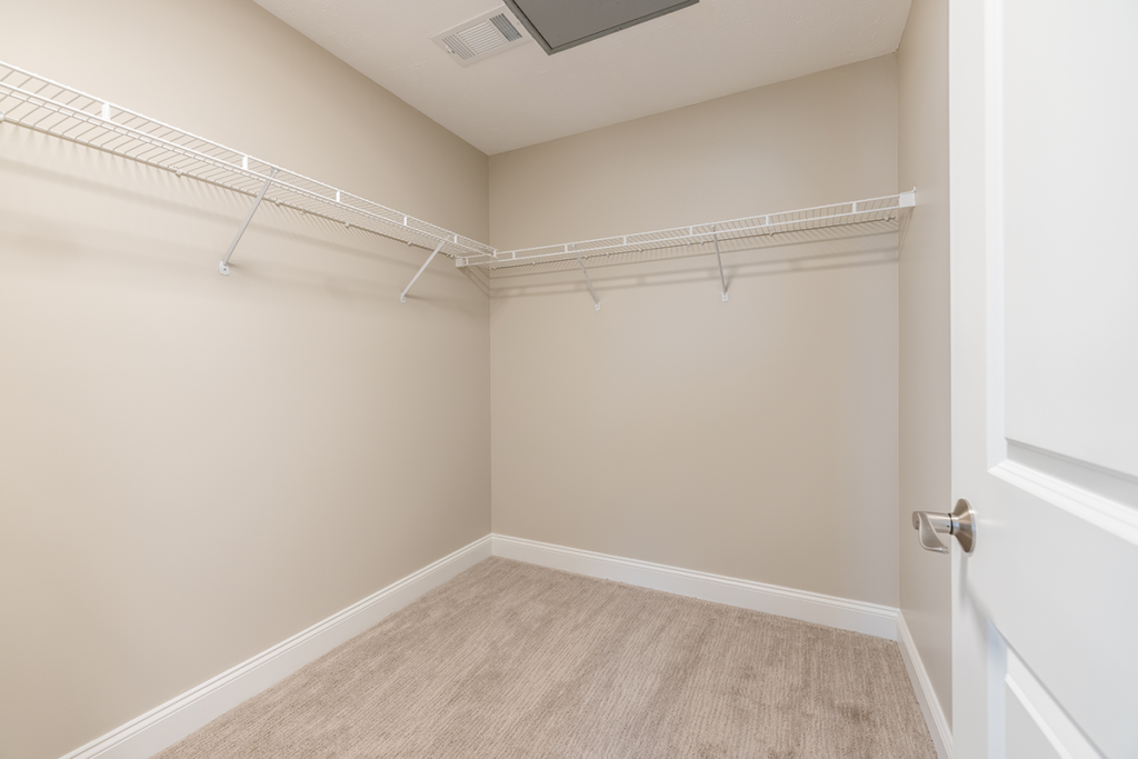 Large master bedroom walk-in closet with extra shelving and carpeted florring