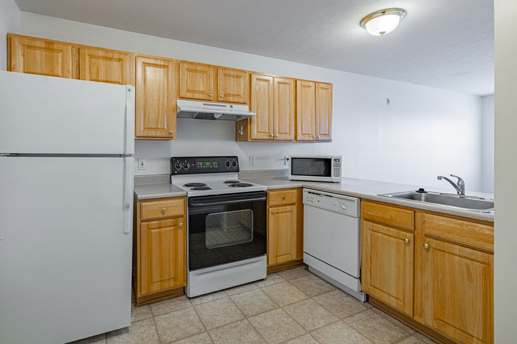 Kitchen view of 2 bedroom apartment with den with ceramic tile flooring with maple cabinetry, dishwasher, refrigerator and electric stove.