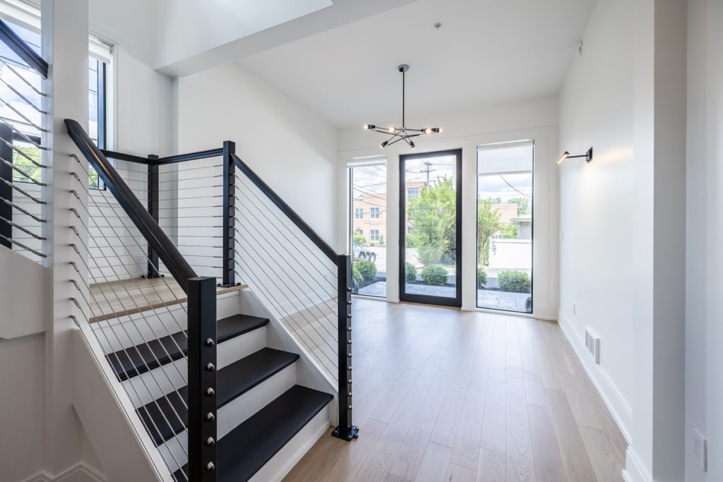 First floor main entrance with access to stairs leading up to second floor. Bright white open space with beautiful hardwood flooring and modern light fixtures.