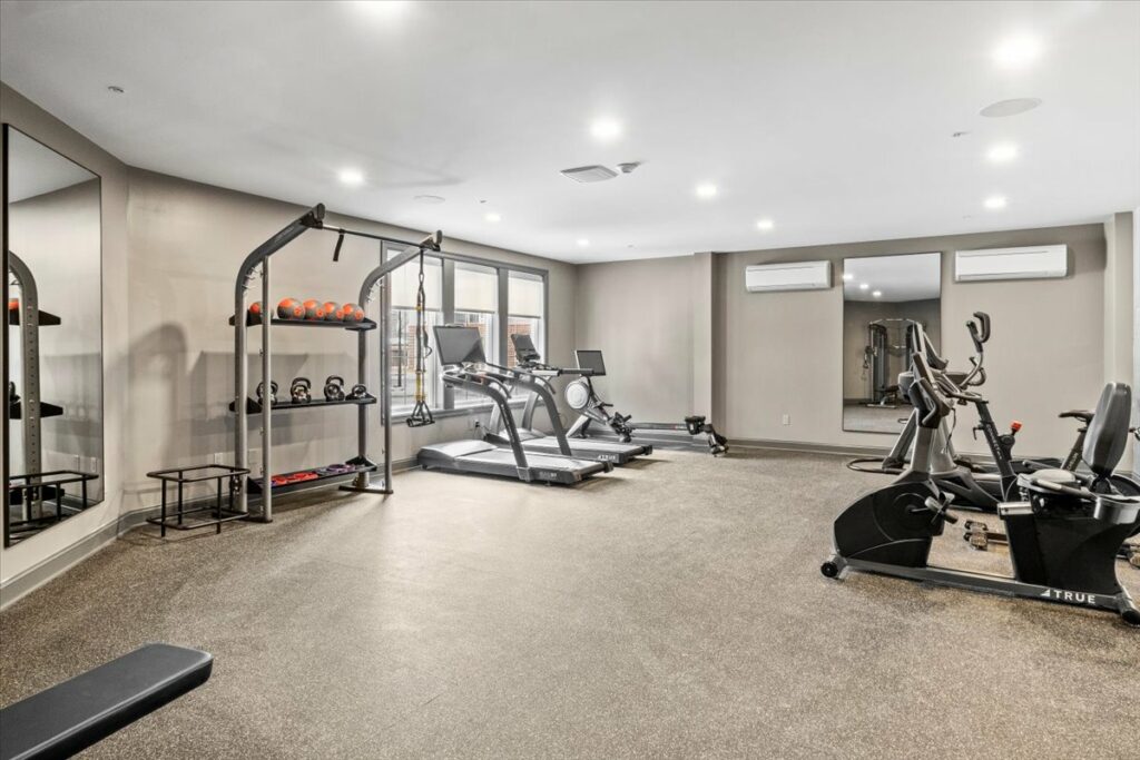Fitness room equipped with treadmill, free weights, and stationary bikes.