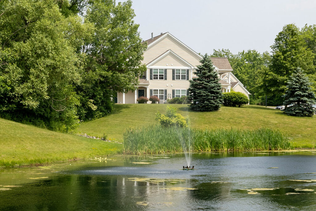 Scenic view of the community pond with the apartment building in the backdrop, offering a harmonious blend of natural beauty and modern living.