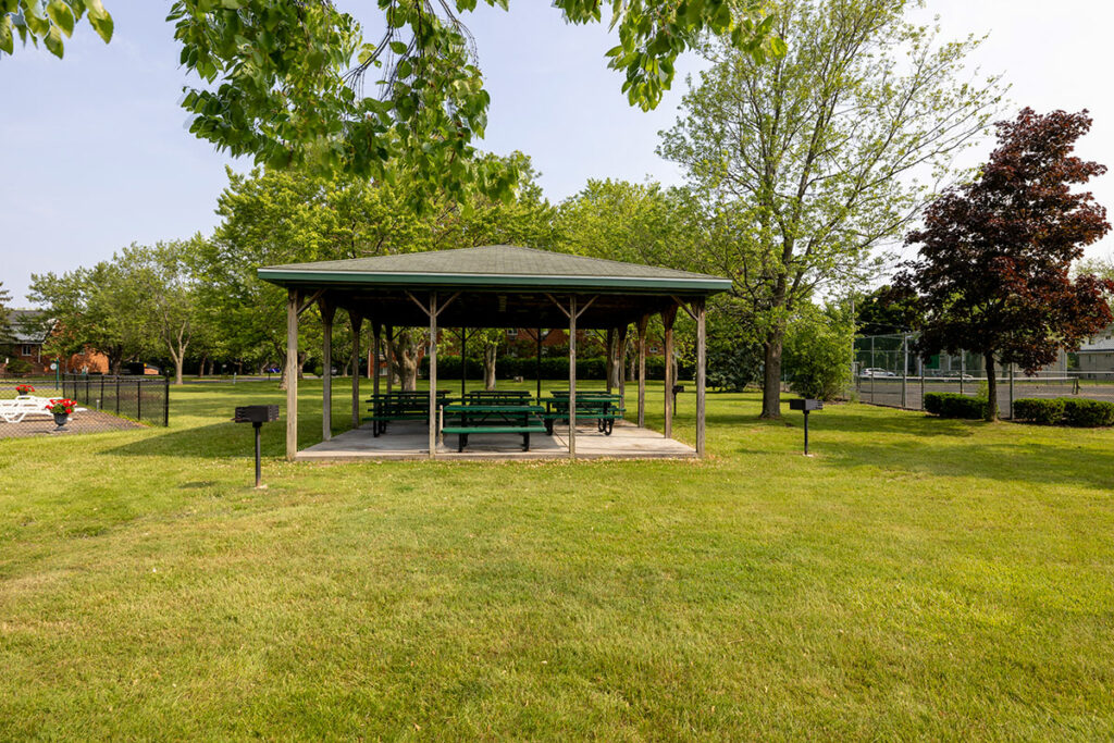 Sheltered picnic area with charcoal grills available for use. The picnic area is equipped with several picnic tables for additional seating options.