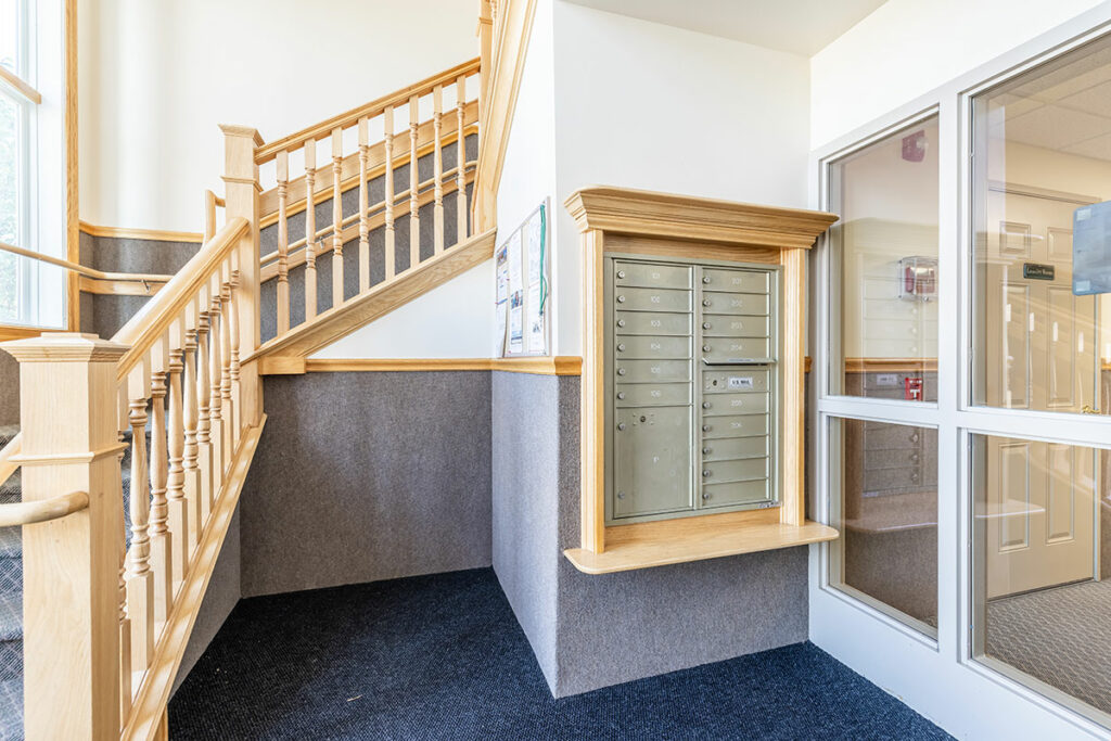 Discover the inviting interior of our apartment building entrance, featuring a staircase leading upstairs and a view of resident mailboxes. Your home at Laurel Springs awaits you with easy access and convenience."