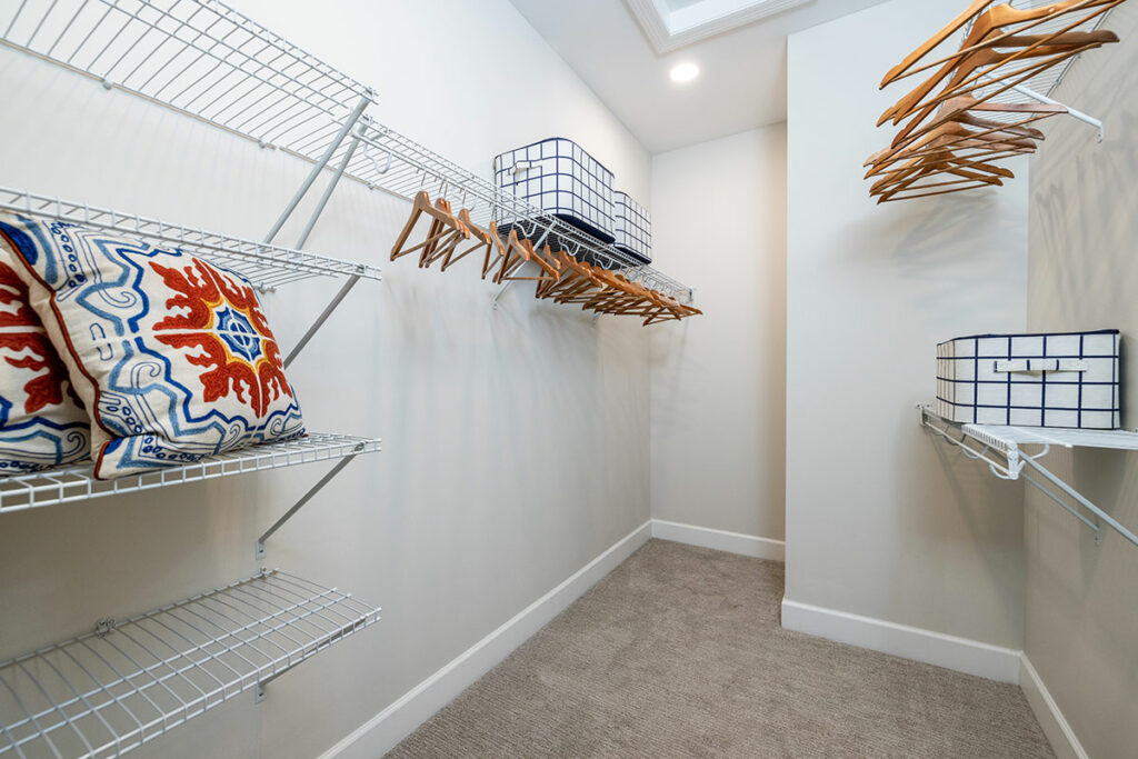 Spacious Walk-In Closet with Abundant Shelving, Ample Storage, and Luxurious Carpeted Flooring.