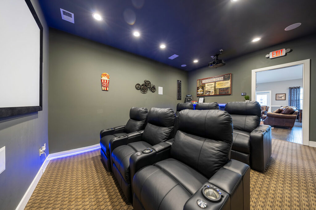 Spacious theater room featuring luxurious leather couches and high-definition projector setup for immersive entertainment experience.